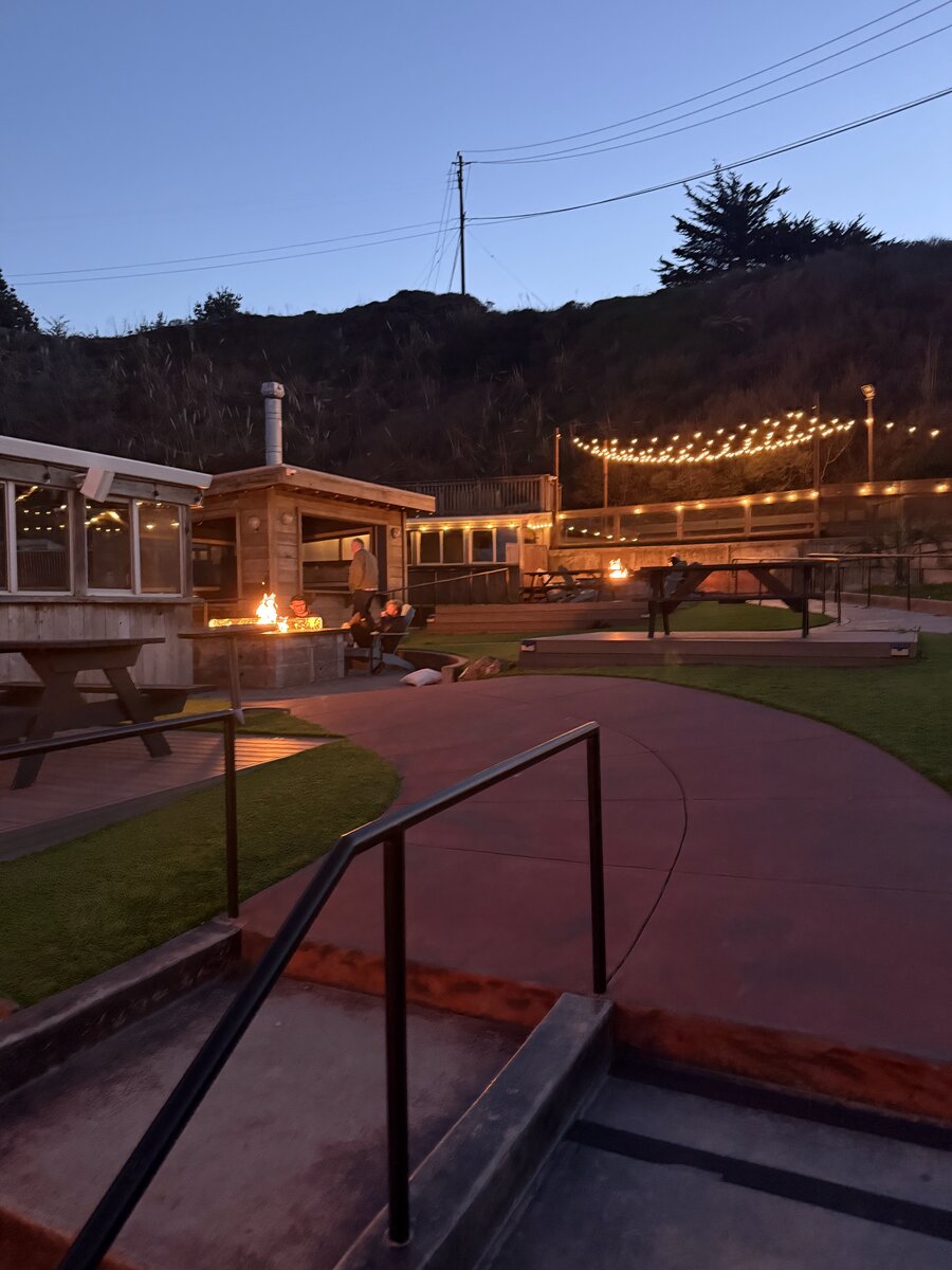 The beer garden at dusk, fire pits glowing