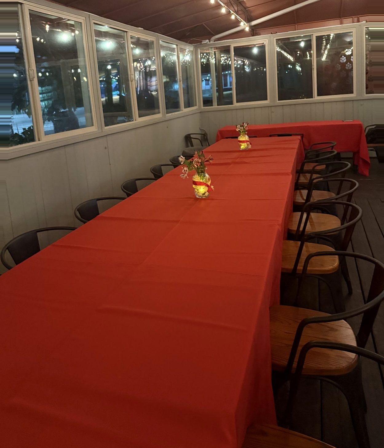 Long-table private dinner set with red linens and fresh flowers