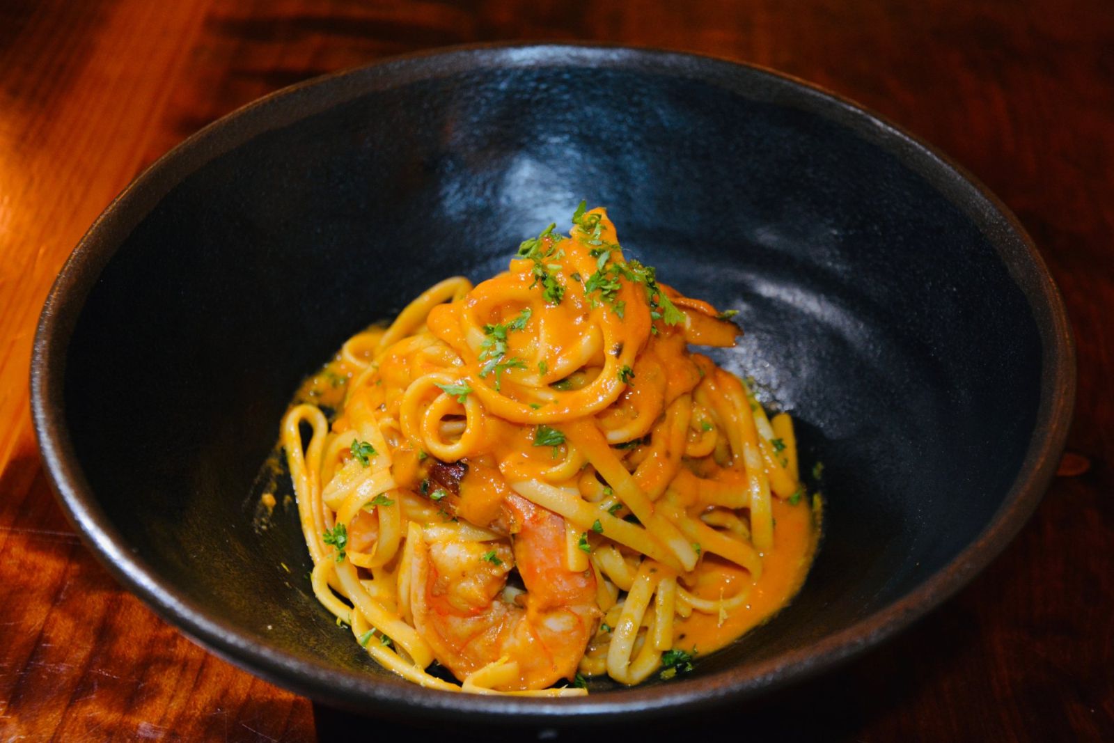 Linguini with prawns in a dark bowl